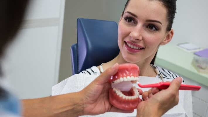 dentist-showing-set-model-teeth-patient